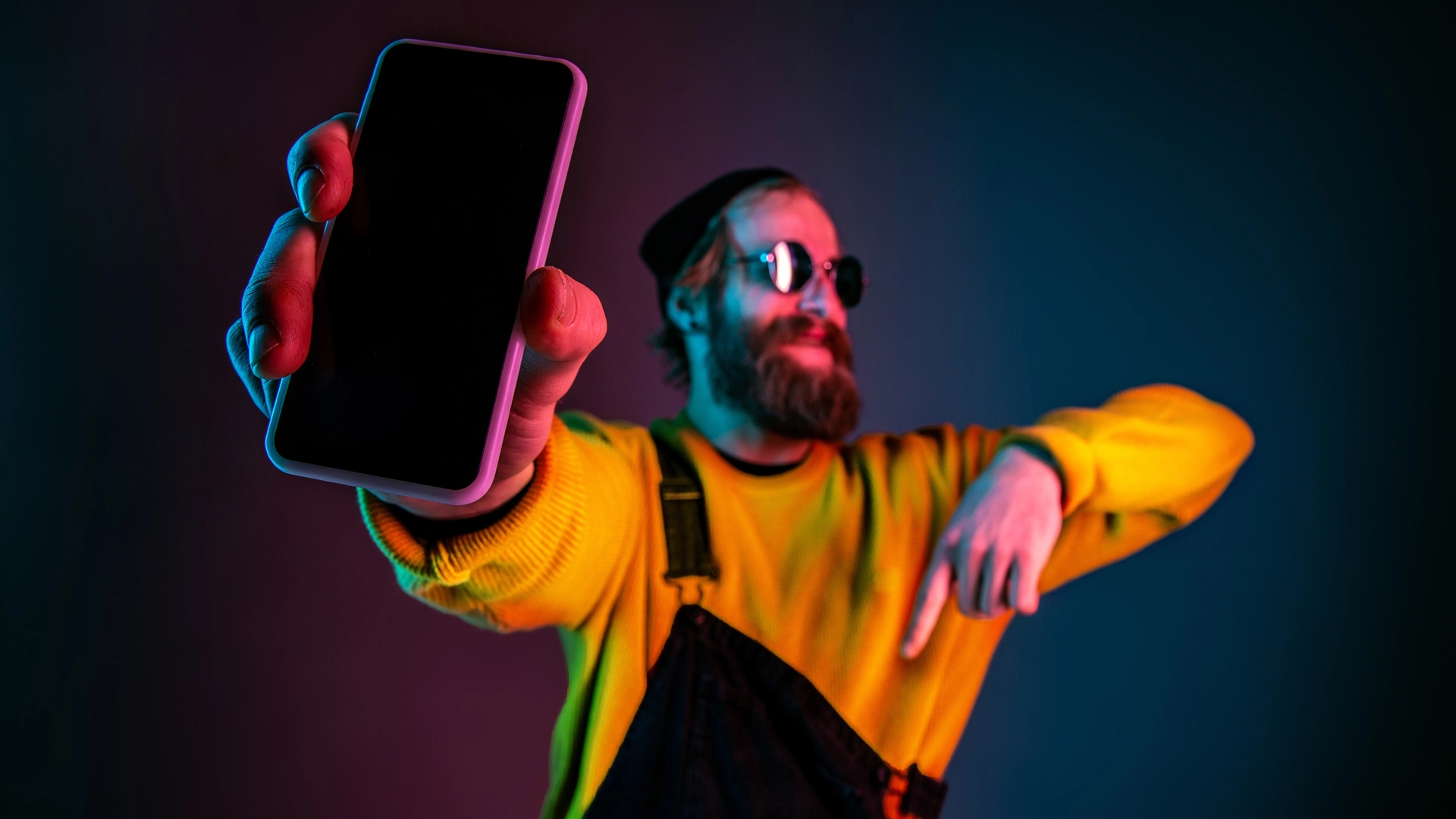 showing-phone-s-blank-screen-caucasian-man-s-portrait-gradient-studio-background-neon-light-beautiful-male-model-with-hipster-style-concept-human-emotions-facial-expression-sales-ad